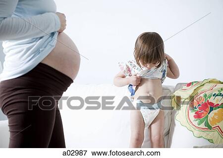 Stock Photo - Girl (2-3) comparing belly with pregnant mother. Fotosearch