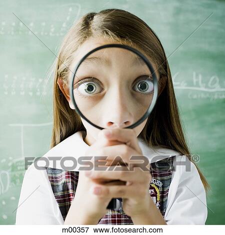Stock Photo - girl in a classroom smiling through a magnifying glass. Fotosearch