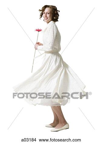 Picture - Happy young woman dancing with gerbera flower, portrait, studio shot. Fotosearch