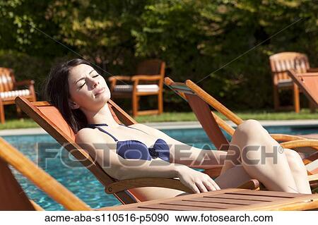 Stock Image - Italy, Amalfi Coast, Ravell, Young woman sunbathing at lounge chair. Fotosearch