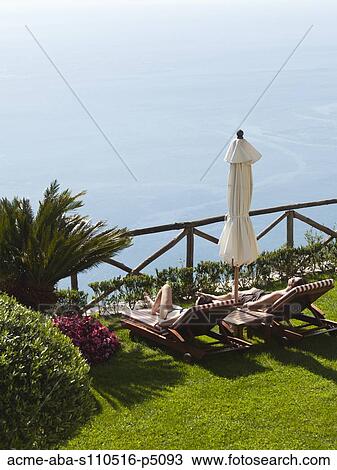 Stock Image - Italy, Amalfi Coast, Ravello, High angle view of lounge chairs with view on sea . Fotosearch