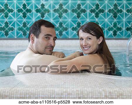 Stock Photo - Italy, Amalfi Coast, Ravello, Mature couple looking over shoulder in swimming pool. Fotosearch