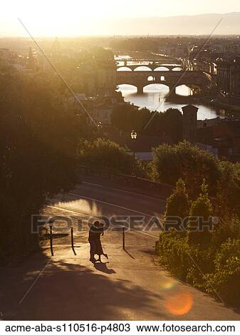 Stock Image - Italy, Florence, Couple embracing with River Arno in background. Fotosearch