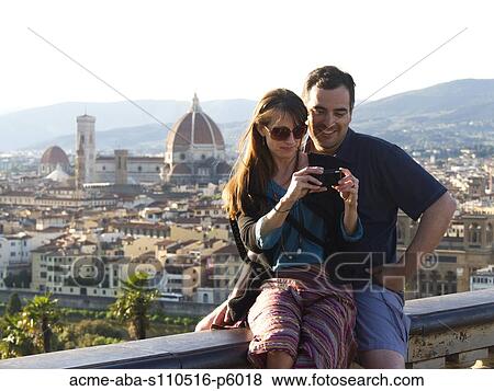 Stock Photo - Italy, Florence, Couple looking at digital camera, townscape in background. Fotosearch