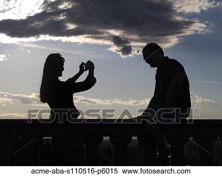 Stock Photography - Italy, Florence, Silhouette of woman photographing man at sunset. Fotosearch