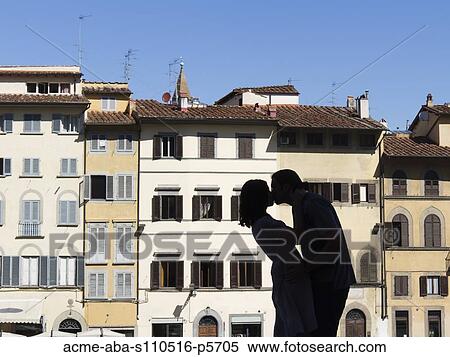 Stock Photography - Italy, Florence, Silhouette of young couple kissing against row of buildings. Fotosearch