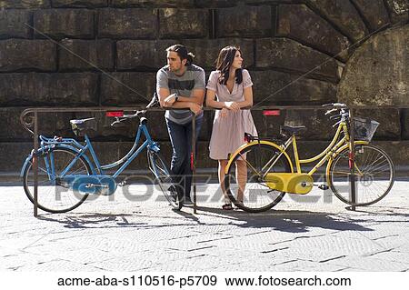 Italy, Florence, Young couple leaning on railings with blue and yellow bikes View Large Photo Image Stock Photo - Italy, Florence, Young couple leaning on railings with blue and yellow bikes. Fotosearch