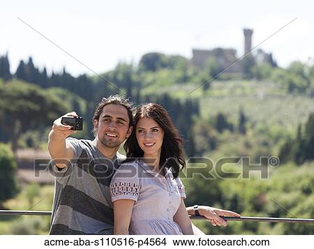 Italy, Florence, Young couple photographing themselves in rural area View Large Photo Image Picture - Italy, Florence, Young couple photographing themselves in rural area. Fotosearch