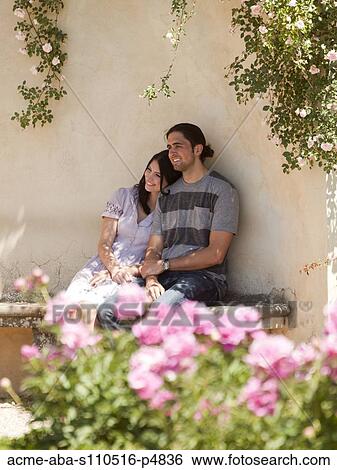 Stock Photograph - Italy, Florence, Young couple sitting by wall. Fotosearch