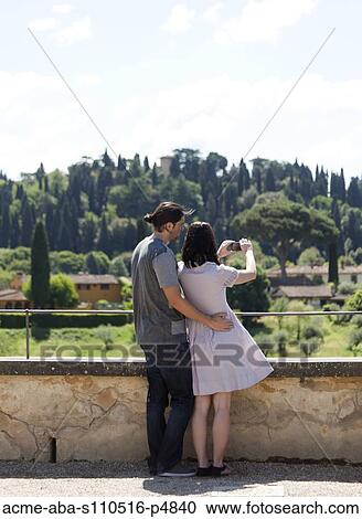 Stock Image - Italy, Florence, Young couple photographing rural landscape. Fotosearch