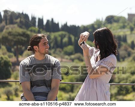 Italy, Florence, Young woman photographing young man in rural area View Large Photo Image Stock Photo - Italy, Florence, Young woman photographing young man in rural area. Fotosearch