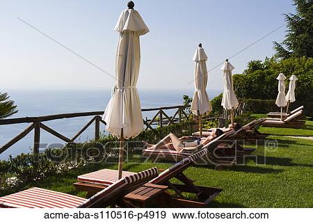 Stock Photo - Italy, Ravello, Amalfi Coast, Couple sunbathing on deck chairs with view on sea. Fotosearch