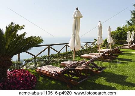 Stock Image - Italy, Ravello, deck chairs on terrace with view on sea. Fotosearch