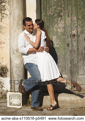 Stock Image - Italy, Ravello, Mature couple kissing by old weathered door. Fotosearch