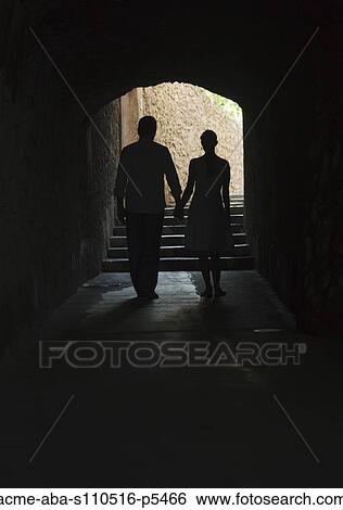 Stock Photograph - Italy, Ravello, Mature couple walking in dark archway. Fotosearch