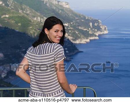 Stock Photo - Italy, Ravello, Portrait of young woman smiling at coast. Fotosearch