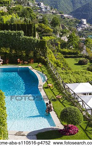 Stock Image - Italy, Ravello, Terrace with outdoor pool and couple kissing. Fotosearch