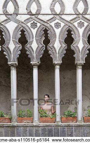 Picture - Italy, Ravello, Woman standing on balcony between ornate columns. Fotosearch