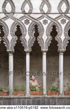 Stock Image - Italy, Ravello, Woman standing on balcony between ornate columns. Fotosearch