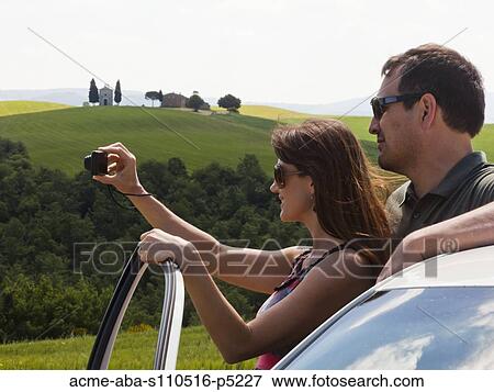 Italy, Tuscany, Couple standing next to car, photographing landscape View Large Photo Image Stock Photo - Italy, Tuscany, Couple standing next to car, photographing landscape. Fotosearch