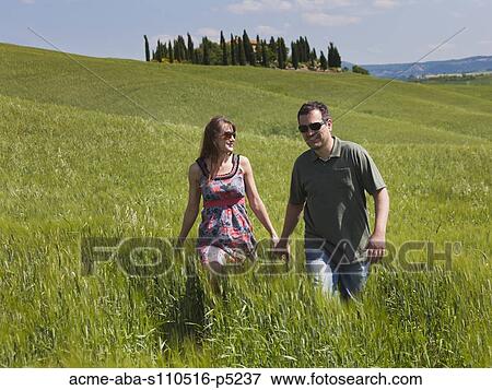 Italy, Tuscany, Couple walking on meadow View Large Photo Image Stock Photo - Italy, Tuscany, Couple walking on meadow. Fotosearch