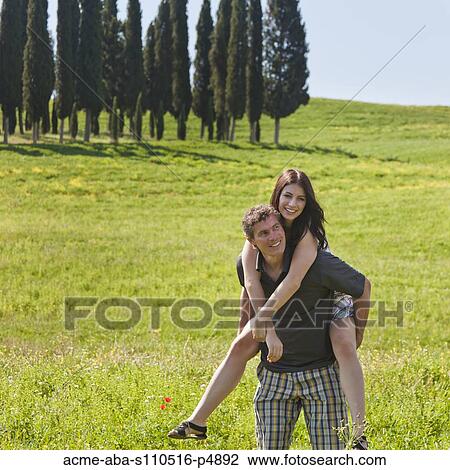 Italy, Tuscany, Man giving piggy back ride to woman on meadow View Large Photo Image Stock Image - Italy, Tuscany, Man giving piggy back ride to woman on meadow. Fotosearch