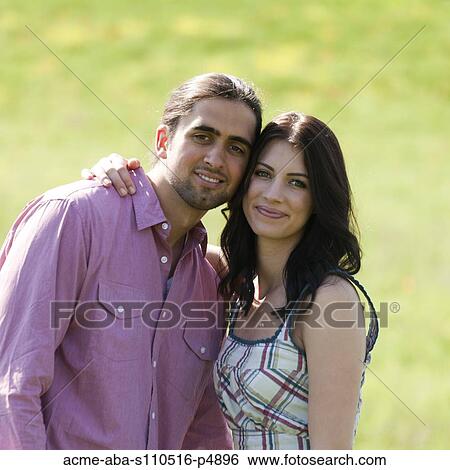 Stock Photograph - Italy, Tuscany, Portrait of young couple on meadow. Fotosearch