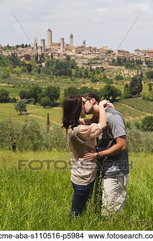 Italy, Tuscany, San Gimignano, Young couple kissing on meadow View Large Photo Image Picture - Italy, Tuscany, San Gimignano, Young couple kissing on meadow. Fotosearch