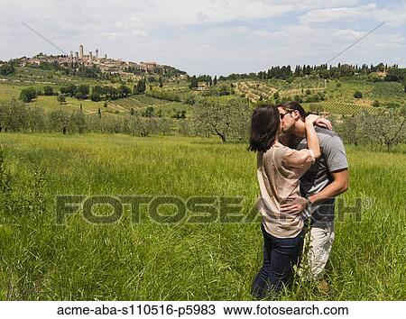 Italy, Tuscany, San Gimignano, Young couple kissing on meadow View Large Photo Image Stock Image - Italy, Tuscany, San Gimignano, Young couple kissing on meadow. Fotosearch
