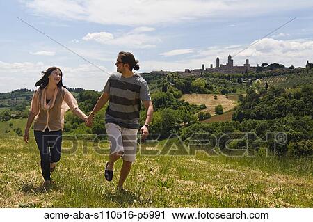 Italy, Tuscany, San Gimignano, Young couple running on meadow View Large Photo Image Stock Image - Italy, Tuscany, San Gimignano, Young couple running on meadow. Fotosearch