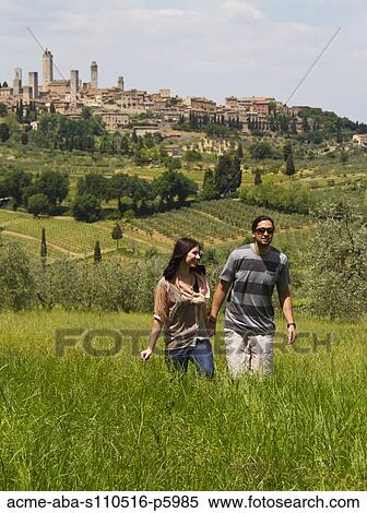 Italy, Tuscany, San Gimignano, Young couple walking on meadow View Large Photo Image Stock Photography - Italy, Tuscany, San Gimignano, Young couple walking on meadow. Fotosearch