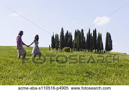 Italy, Tuscany, Val D'Orcia, Couple walking in meadow View Large Photo Image Stock Photography - Italy, Tuscany, Val D'Orcia, Couple walking in meadow. Fotosearch