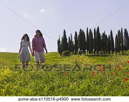 Italy, Tuscany, Val D'Orcia, Young couple walking on meadow View Large Photo Image Stock Image - Italy, Tuscany, Val D'Orcia, Young couple walking on meadow. Fotosearch