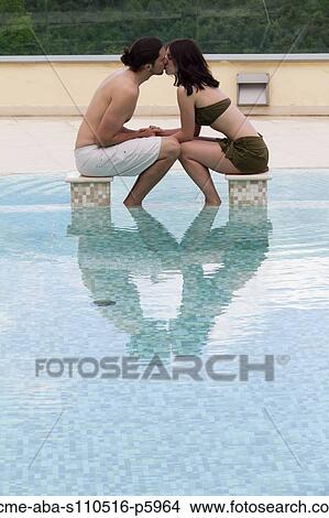 Picture - Italy, Tuscany, Young couple kissing in pool. Fotosearch