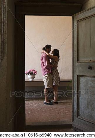 Stock Image - Italy, Tuscany, Young couple kissing in old house. Fotosearch
