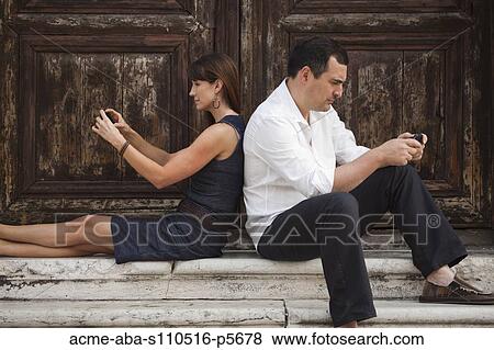 Italy, Venice, Couple sitting on steps, using smart phones View Large Photo Image Stock Photo - Italy, Venice, Couple sitting on steps, using smart phones. Fotosearch