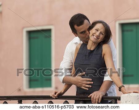 Stock Image - Italy, Venice, Mature couple embracing on bridge. Fotosearch