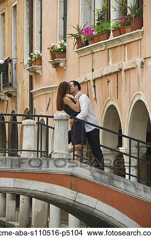 Picture - Italy, Venice, Mature couple kissing on bridge. Fotosearch