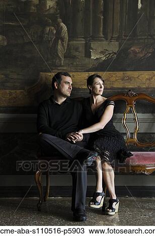 Stock Image - Italy, Venice, Mature couple sitting on old chair. Fotosearch