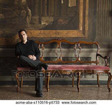 Stock Image - Italy, Venice, Mature man posing in museum hall. Fotosearch