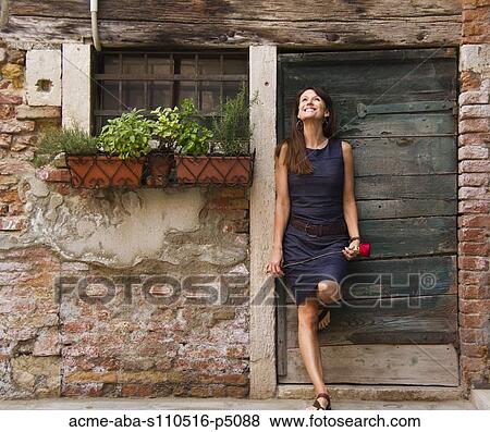 Italy, Venice, Mature woman holding red rose and standing against door View Large Photo Image Stock Photo - Italy, Venice, Mature woman holding red rose and standing against door. Fotosearch