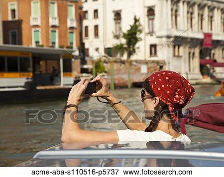 Italy, Venice, Mature woman taking photographs while traveling on canal View Large Photo Image Stock Photo - Italy, Venice, Mature woman taking photographs while traveling on canal. Fotosearch