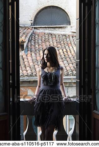 Stock Photo - Italy, Venice, Portrait of young woman with roofs in background. Fotosearch