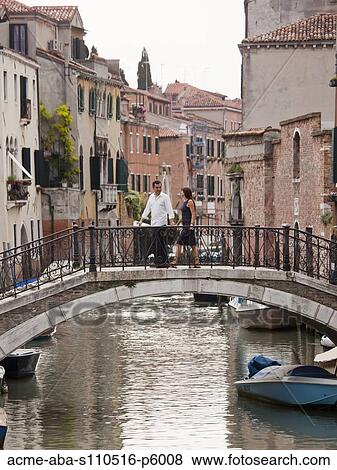 Stock Photo - Italy, Venice, Romantic couple walking on footbridge over canal. Fotosearch
