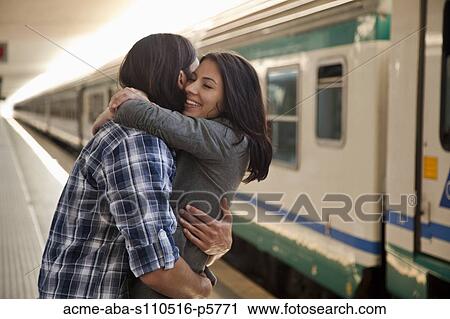 Stock Image - Italy, Venice, Young couple embracing on railway station. Fotosearch