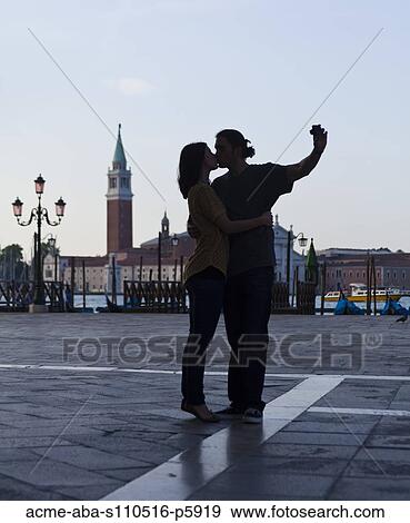 Italy, Venice, Young couple kissing and photographing self, San Giorgio Maggiore church in background View Large Photo Image Stock Photo - Italy, Venice, Young couple kissing and photographing self, San Giorgio Maggiore church in background. Fotosearch