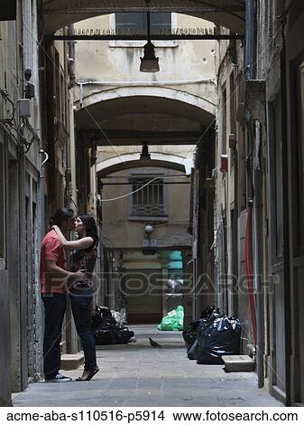 Picture - Italy, Venice, Young couple kissing in narrow street. Fotosearch