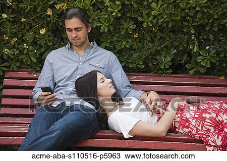 Stock Image - Italy, Venice, Young couple relaxing on bench. Fotosearch