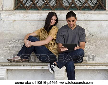 Italy, Venice, Young couple sitting on bench, using digital tablet View Large Photo Image Stock Photography - Italy, Venice, Young couple sitting on bench, using digital tablet. Fotosearch