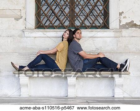 Italy, Venice, Young couple sitting back to back on bench View Large Photo Image Stock Photo - Italy, Venice, Young couple sitting back to back on bench. Fotosearch